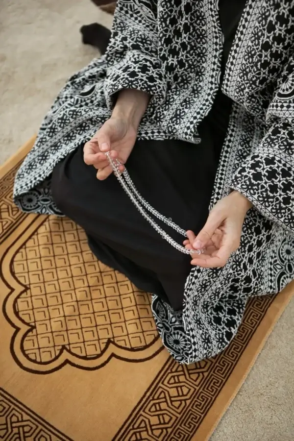 Détail d’un moment de prière sur tapis de prière avec tasbih entre les mains